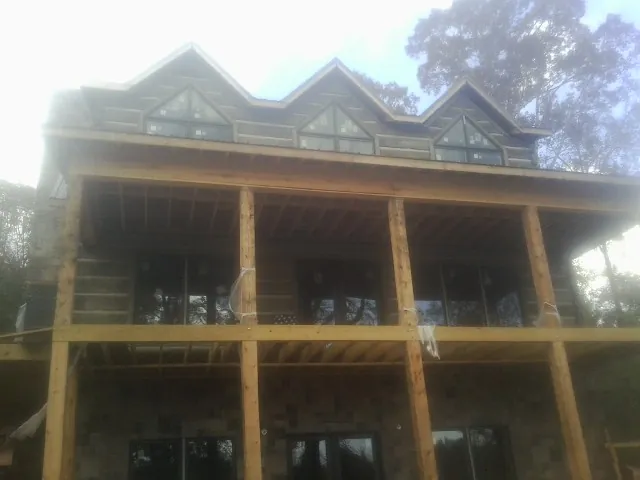 Dormers and porch framing on a large log home under construction — Roof Coating work by our crew in Sellers
