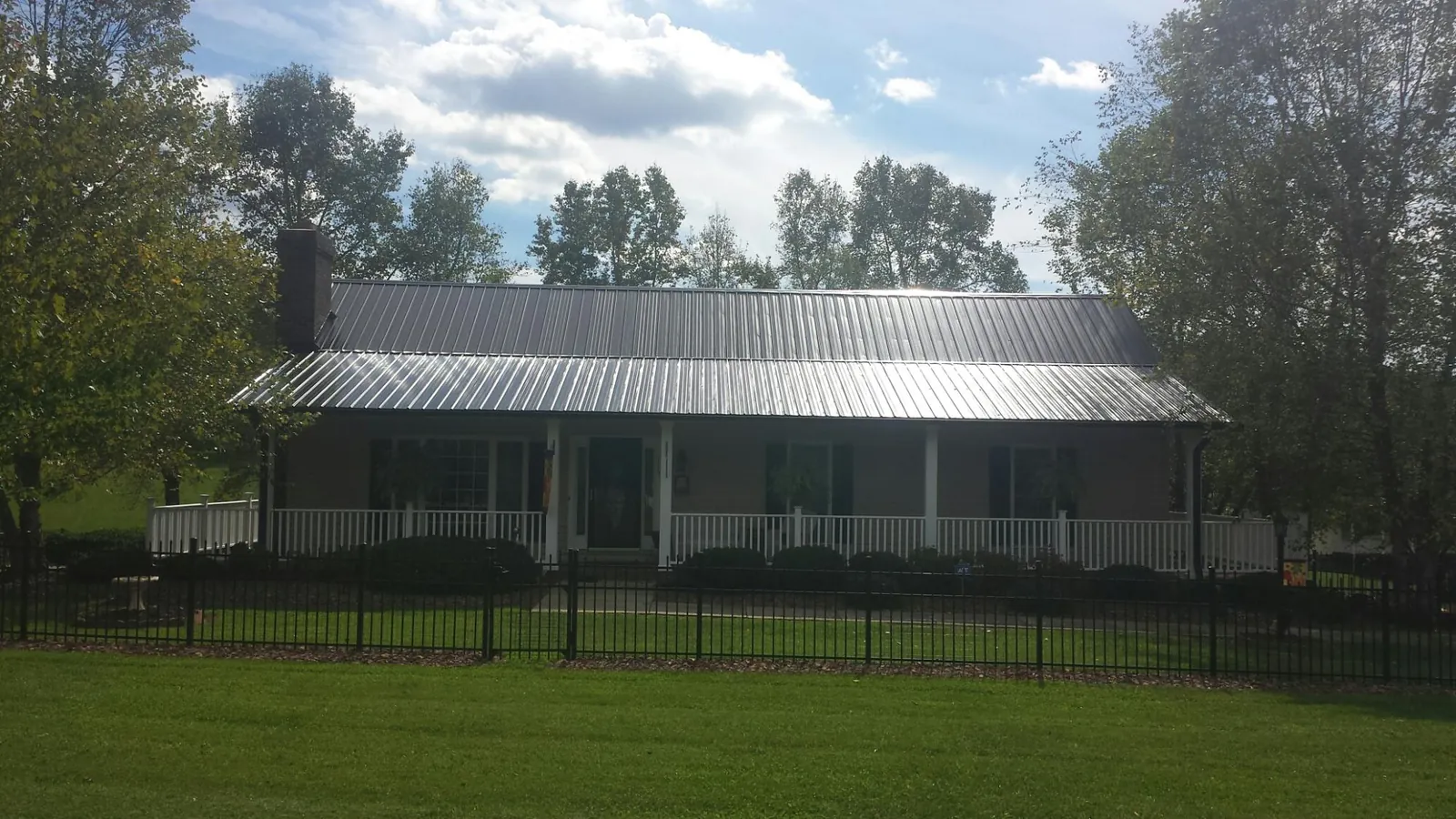 Gray metal roof on a brick ranch with a full width front porch — Gutter Guard Installation work by our crew in Sellers