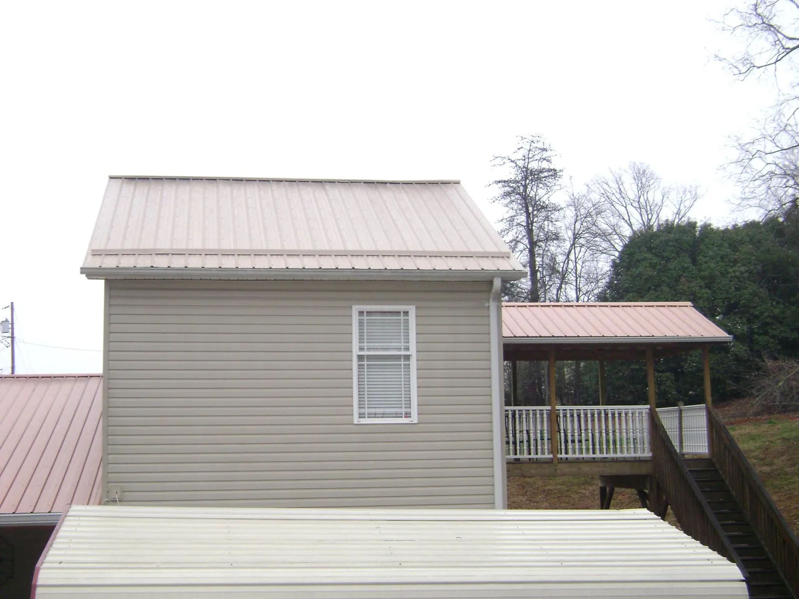 Tan metal roofs on a two story addition and attached porch, from a Roof Replacement job in Sellers