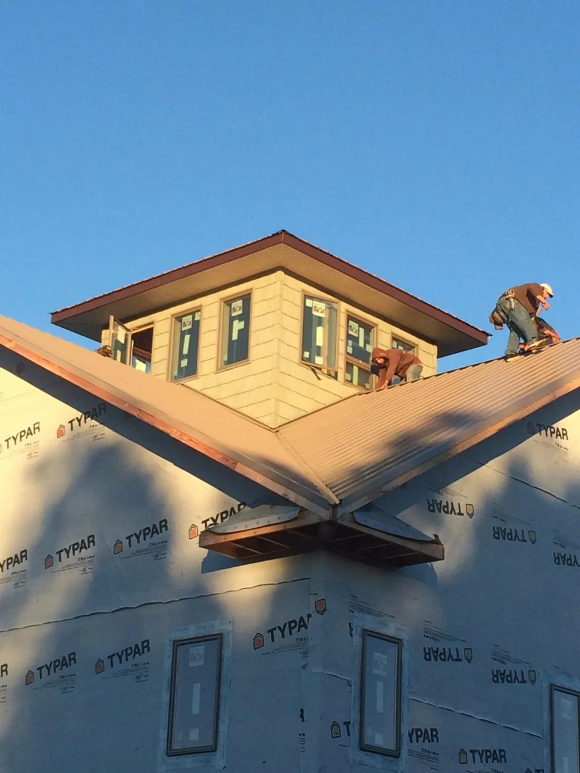 Roofers working around a rooftop cupola on a new metal roof at sunset — Roof Waterproofing in Sellers by Roofing Brothers